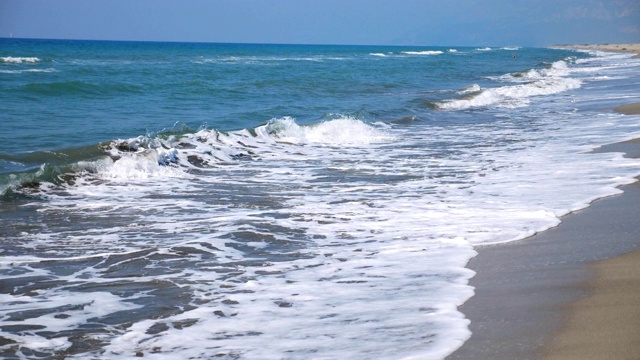 空旷的沙滩和巨大的海浪冲击着海岸线。热带度假胜地，阳光明媚的一天。风景优美的海景。慢动作视频素材