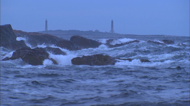 海浪冲击着附近灯塔下面的岩石海岸线。视频素材