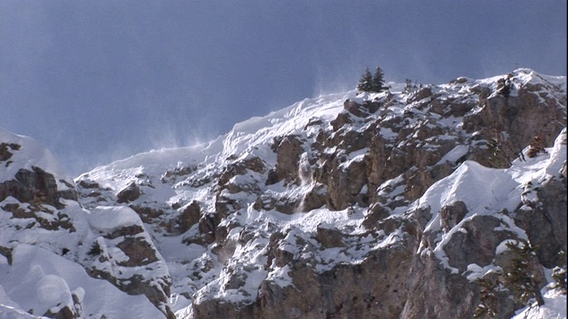 一个容易发生雪崩的雪帽在山顶边缘。视频素材