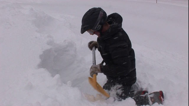 一名救援人员在一座雪山的一侧挖了一个洞。视频素材