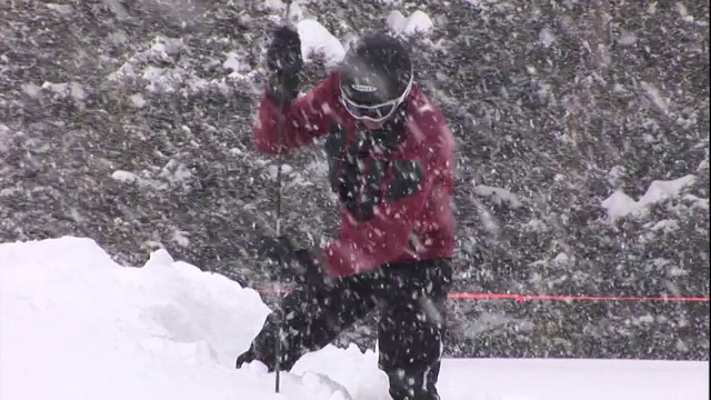 一名救援人员将一根长杆插进一层厚厚的雪中。视频素材