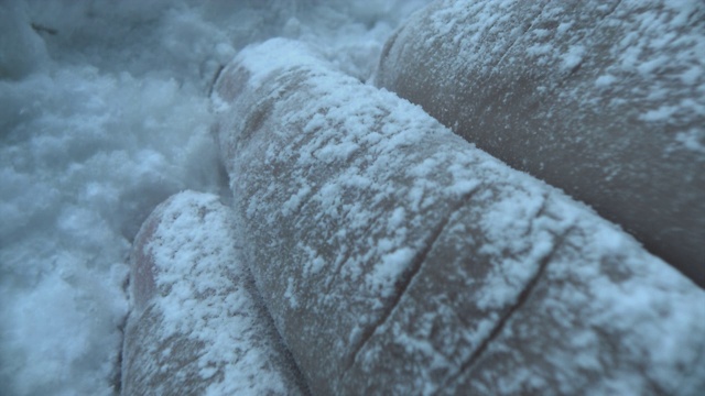 在巴塔哥尼亚的一场暴风雪中，一名手指冻僵的户外男子脸朝下躺在雪地里，以求得生存。视频素材