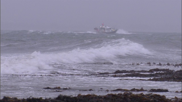 一艘船在暴风雨中穿过波涛汹涌的海浪。视频素材