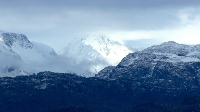 雪覆盖了山峰;一架直升飞机飞过森林和海洋。视频素材