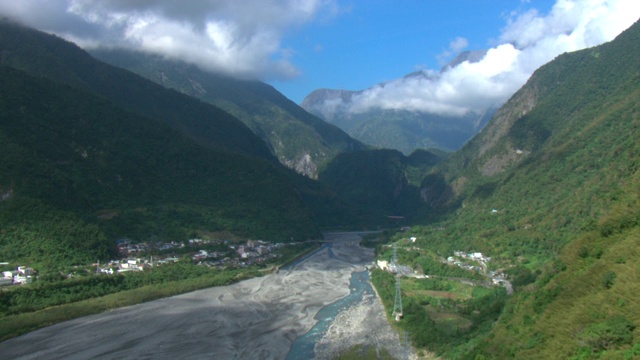 一个社区坐落在郁郁葱葱的群山之间的河岸上。视频素材