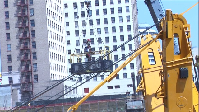 起重机用篮子把一名建筑工人吊在空中。视频素材