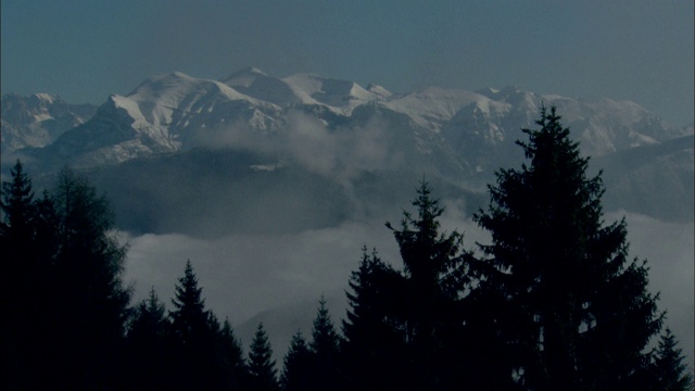 白云躺在白雪皑皑的山峰下。视频素材