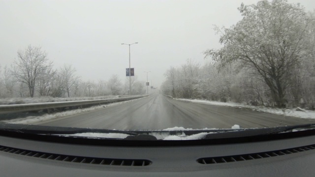 汽车POV在积雪覆盖的路上行驶，先下起了雪。视频素材