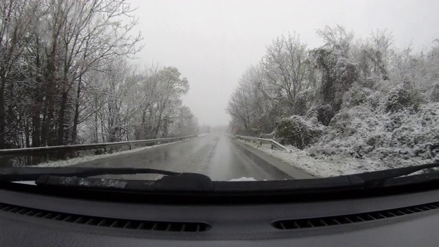 汽车POV在积雪覆盖的路上行驶，先下起了雪。视频素材