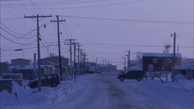 在阿拉斯加的一个小镇上，车辆行驶在积雪覆盖的道路上。视频素材