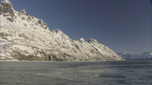 浮冰漂浮在海湾的表面，靠近冰雪覆盖的海岸山脉。视频素材