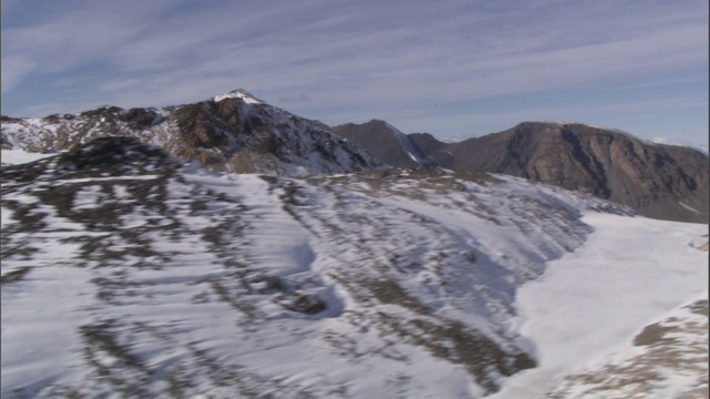 雪覆盖了山谷中一条土路附近的崎岖地形。视频素材