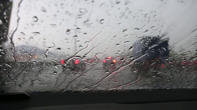 汽车在行驶中，雨滴顺着挡风玻璃流下。在视图中。视频素材