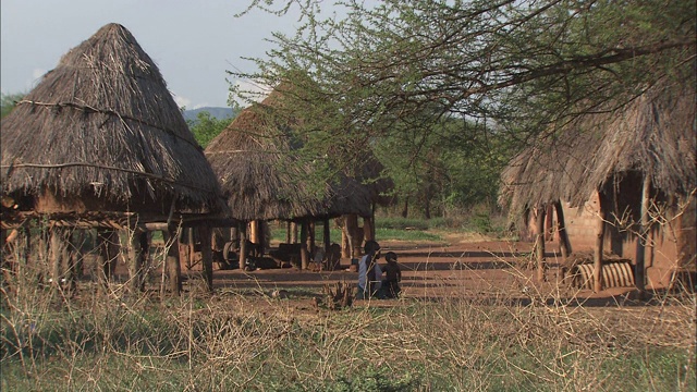 母亲和孩子坐在茅草屋顶的小屋中。视频素材