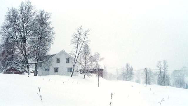 挪威乡村的冬季景观与经典的木屋在大雪期间视频素材