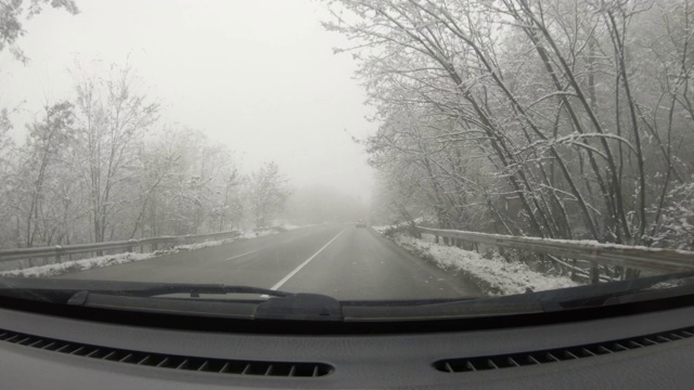 汽车POV在积雪覆盖的路上行驶，先下起了雪。视频素材