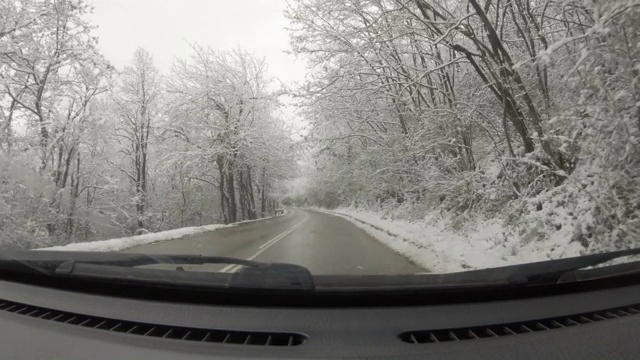 汽车POV在积雪覆盖的路上行驶，先下起了雪。视频素材