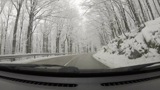 汽车POV在积雪覆盖的路上行驶，先下起了雪。视频素材