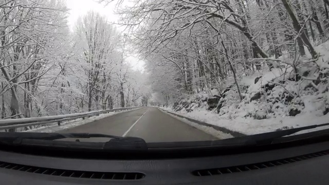 汽车POV在积雪覆盖的路上行驶，先下起了雪。视频素材