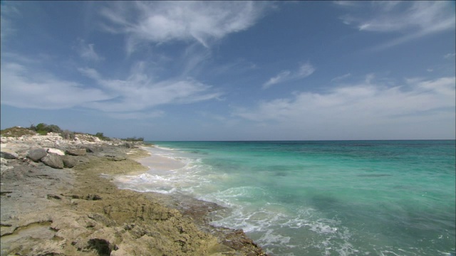 蓝色的海浪冲刷着布满岩石的海岸。视频素材