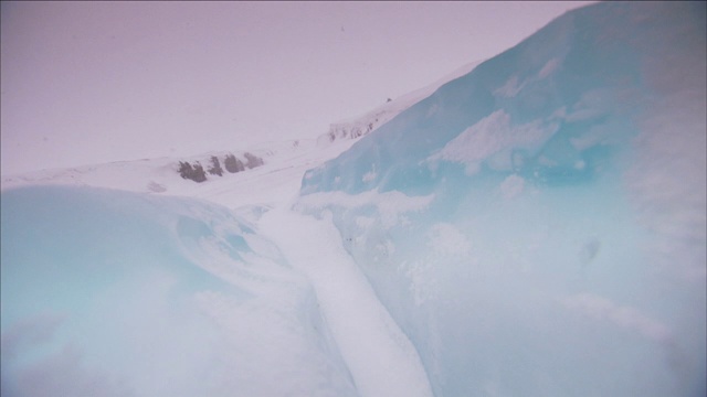 在湖岸附近，蓝色的冰上覆盖着一片片的雪。视频素材