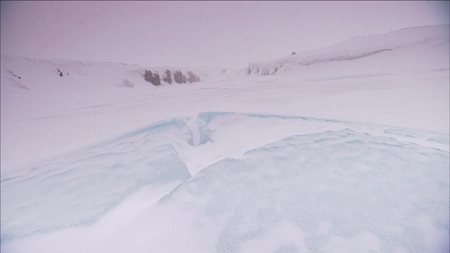 在湖岸附近，蓝色的冰上覆盖着一片片的雪。视频素材