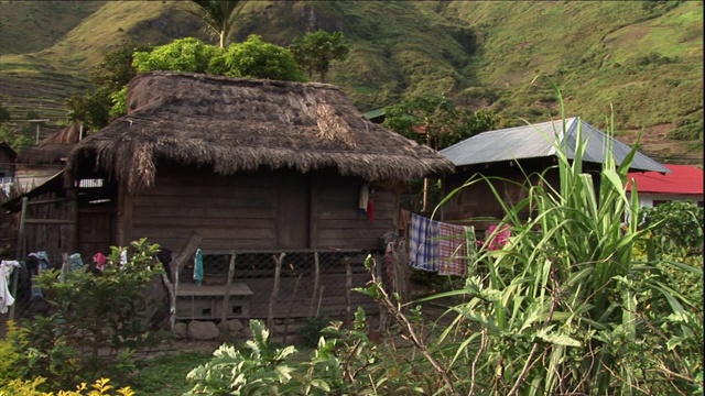 在茅草屋顶的小屋外，毯子挂在晾衣绳上。视频素材