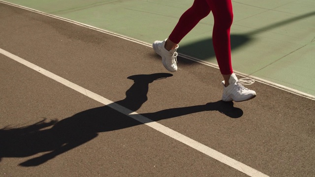 近距离女性脚慢跑在教练员在轨道上。女孩在户外的轨道上跑步视频素材