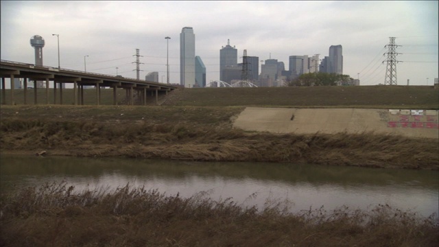 车辆穿过一条横跨达拉斯天际线附近河流的高速公路大桥。视频素材