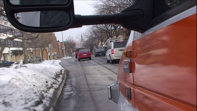 一辆汽车在积雪的城市街道上跟随着其他车辆行驶。视频素材