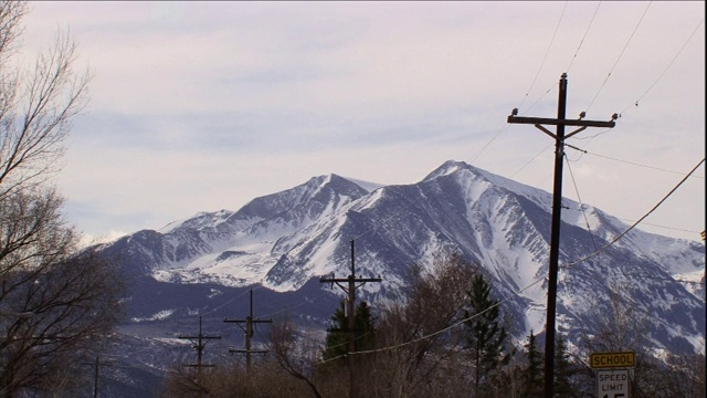 电线杆排列在一座雪山的山脚上。视频素材