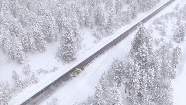 无人机:铲雪车清理穿过森林的乡村道路。视频素材