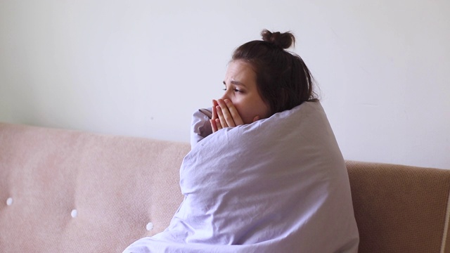 生病的年轻女子因喉咙痛而坐在家里咳嗽。视频素材