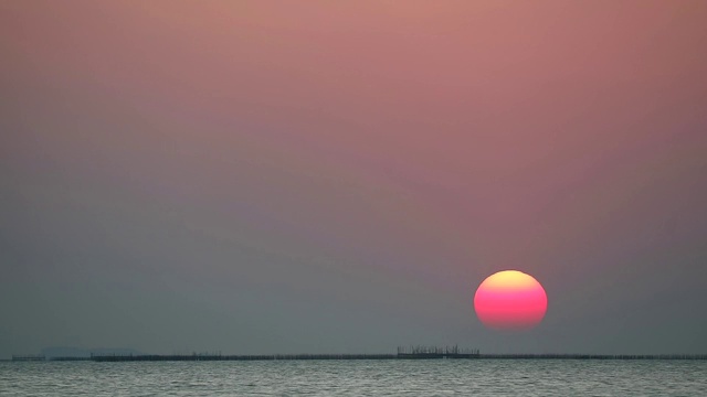 日落在红色的晴朗的天空在灰色的橙色云在海上时间流逝视频素材