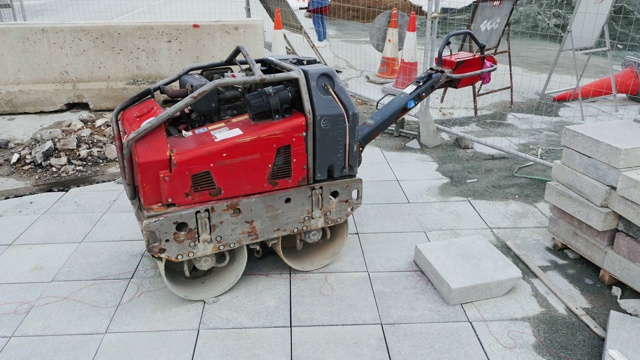 正在重建的封闭街道上的压路机。红色小压路机靠近道路护栏和围栏。街下重建。视频素材