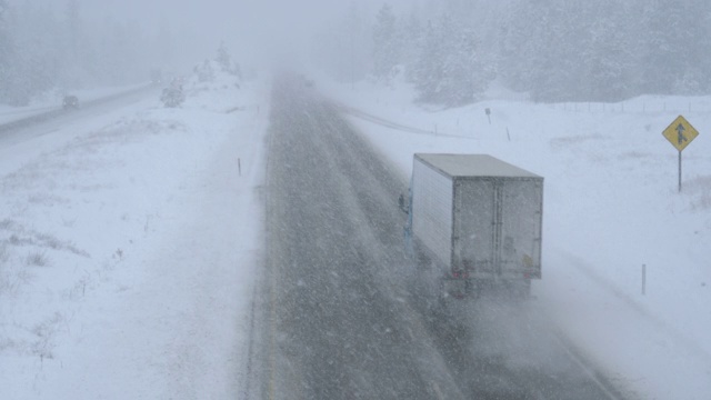 卡车和汽车在暴风雪中沿着一条危险的乡村道路前进视频素材