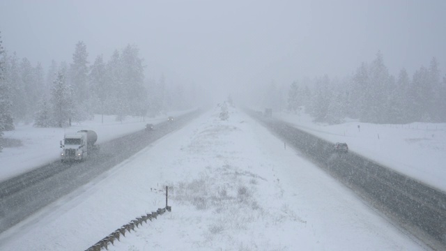 汽车和卡车在暴风雪中小心地在州际公路上行驶。视频素材