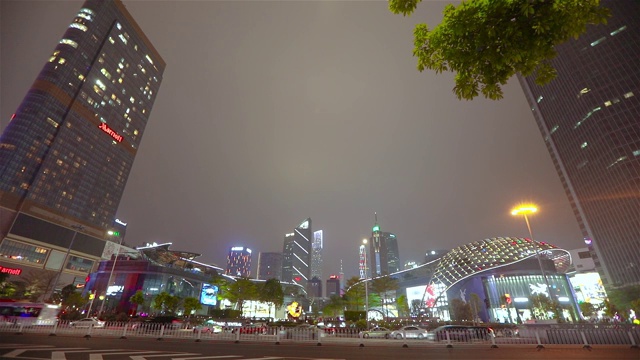 汽车在夜间以高楼大厦为背景行驶。瓜州，汽车在路上行驶，摩天大楼在背景中，时光流逝视频素材