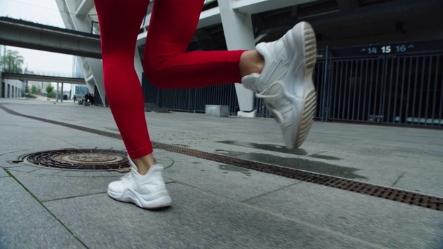 近距离观察女性跑步者在城市街道上慢跑的双腿。运动女孩训练跑步。视频素材