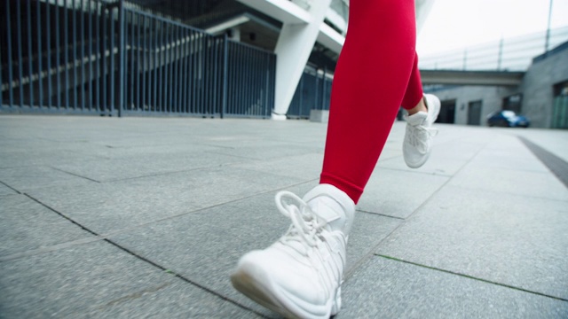 近距离观察女性在城市街道上奔跑的双腿。女人的腿在户外慢跑。视频素材