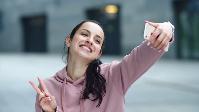 特写的快乐的女人摆姿势自拍。快乐的女人显示胜利的迹象视频素材