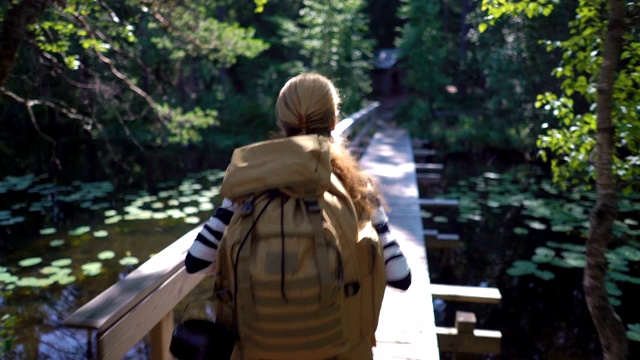 一个年轻女子背着一个大背包徒步旅行森林小径视频素材