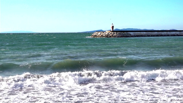 冬季的灯塔和海浪在海滩上溅起水花视频素材