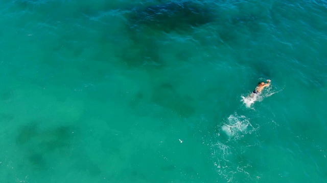 航空,俯视图。在蓝绿色的海水里，有一个人在游泳。夏天炎热的晴天视频素材