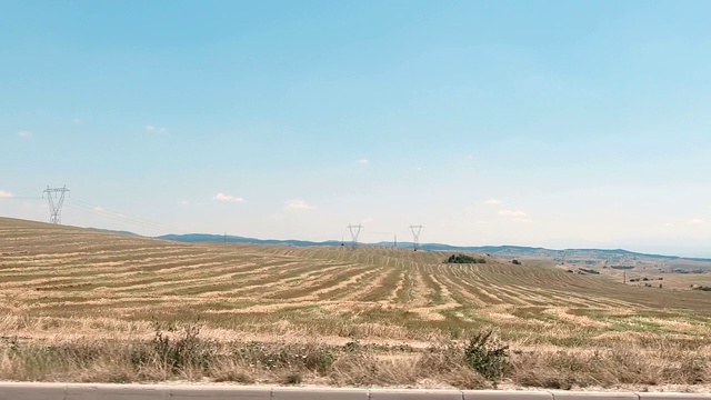 沿着乡村行驶，旁边是电线塔和田地视频素材