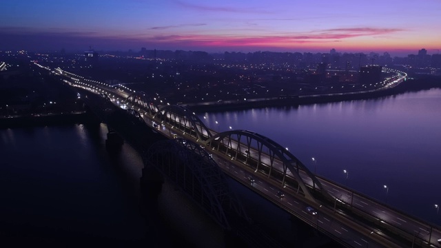 4 k的视频。城市上空是黎明，汽车在桥上行驶。太阳从城市上空升起。航空摄影视频素材