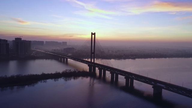 4 k的视频。城市上空是黎明，汽车在桥上行驶。太阳从城市上空升起。航空摄影视频素材