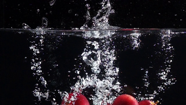 超级慢镜头:在黑色背景下，苹果掉进淡水中视频素材