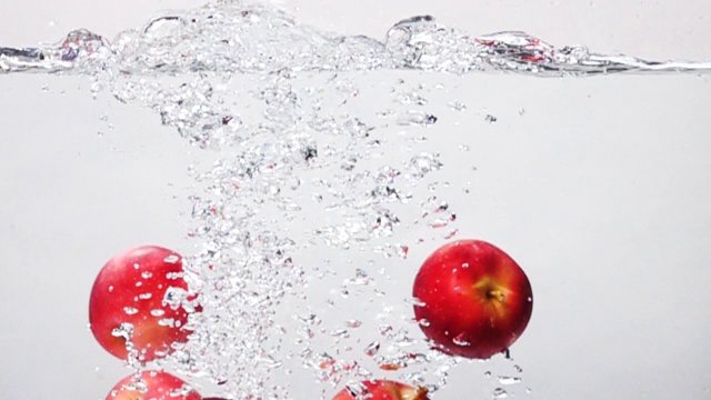超级慢镜头:在白色背景下，苹果掉进淡水中视频素材