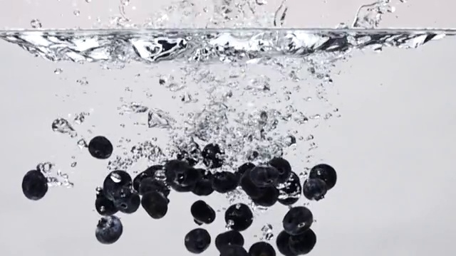 超级慢动作:蓝莓滴入淡水在白色的背景视频素材